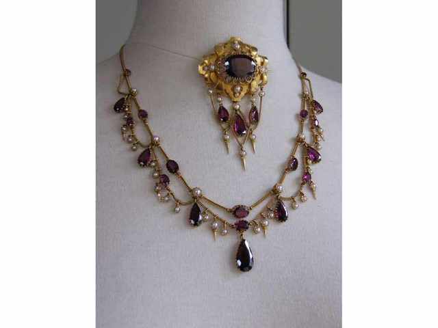 Collier draperie et broche ovale, or jaune à pampilles, sertis de grenats ovales ou poires et demi perles, travail français vers 1850. Collier draperie et broche ovale, or jaune à pampilles, sertis de grenats ovales ou poires et demi perles, travail français vers 1850.